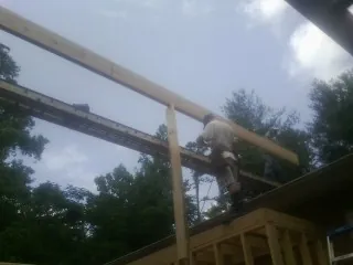 Carpenter setting a ridge beam over a new addition frame — Ice Dam Removal by Roofing Brothers in Parksley