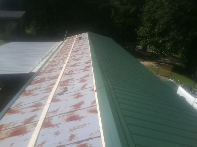 Old rusted panels beside newly installed green metal roofing — Wind Damage Roof Repair by Roofing Brothers in Parksley