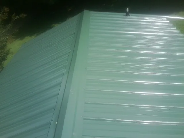 New green metal panels meeting at the ridge of a roof — Flat Roof Repair work by our crew in Parksley