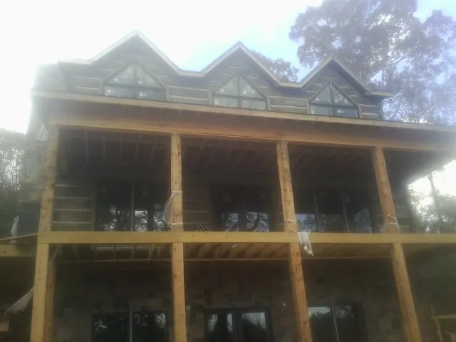 Dormers and porch framing on a large log home under construction — Roof Coating work by our crew in Parksley