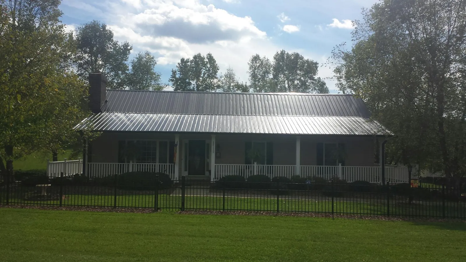 Gray metal roof on a brick ranch with a full width front porch — Gutter Guard Installation work by our crew in Parksley