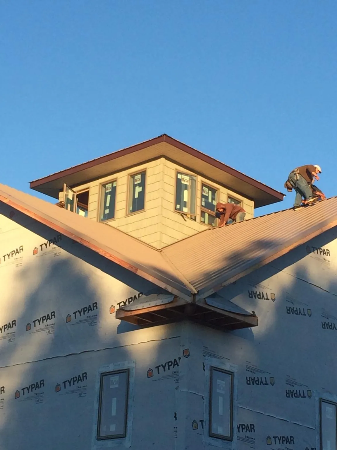 Roofers working around a rooftop cupola on a new metal roof at sunset — Roof Waterproofing in Parksley by Roofing Brothers